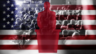 Silhouette of a male politician at a podium. Background shows a diverse crowd of people sitting in an auditorium, embossed over an image of the United States flag.