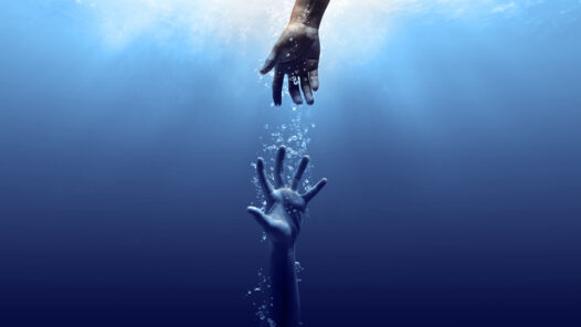 Hand reaching down into the water to grab the out stretched arm of someone sinking in the water.