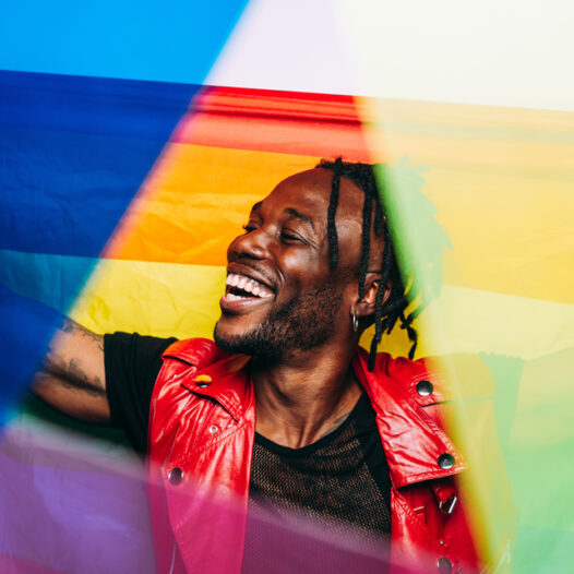 Black man smiling overlaid with pride flags and rainbow colors.