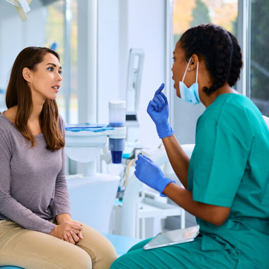 Female dentist and female patient talking in a dental office.